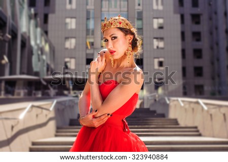 A beautiful girl in a long red dress and a royal crown