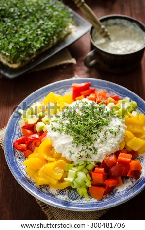 Colorful salad with baked yellow and red bell peppers, leek, tartar sauce and cuckooflower