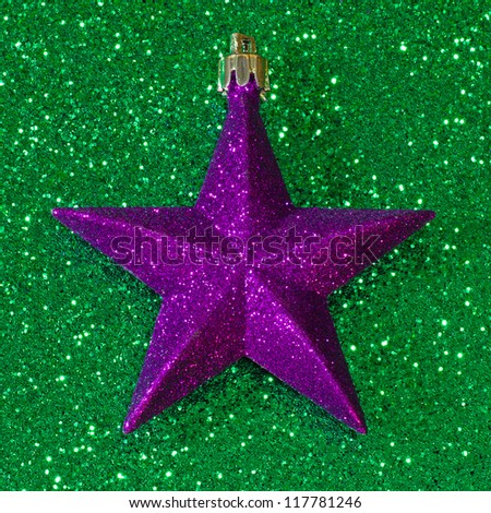 Purple Christmas star decoration on green glitter background