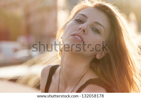 Attractive young blonde woman looking at the camera with her head thrown back in the golden glow of evening sunlight
