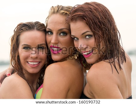 Happy young girlfriends very happy and smiling, looking at camera in swimsuit with wet hair.