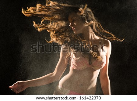 Woman shaking head in lingerie with powder