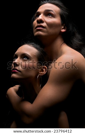 Multiracial couple embracing under dim light.