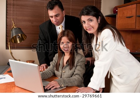 Group of coworkers sharing information and looking at computer in small business.