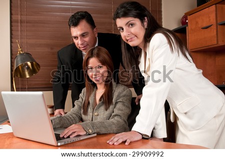 Group of coworkers sharing information and looking at computer in small business.