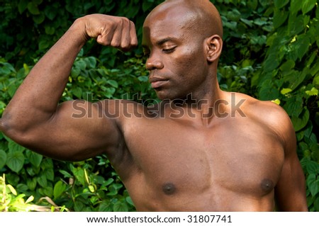 Young african american showing muscle and powerful biceps.