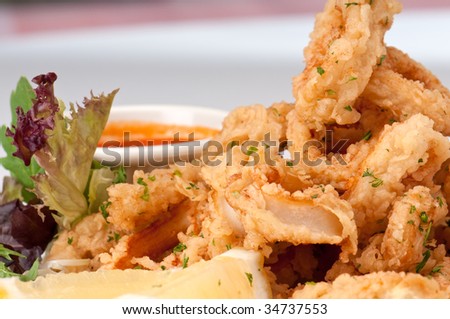 Plate of fried calamari served with marinara sauce and lemon.
