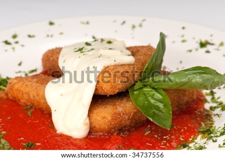 Plate of fried mozzarella with marinara sauce, parsley and melting mozzarella on top.
