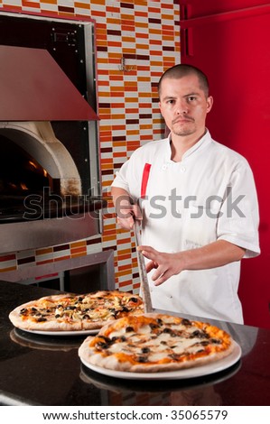 Young hispanic cook getting pizza into a restaurant counter.