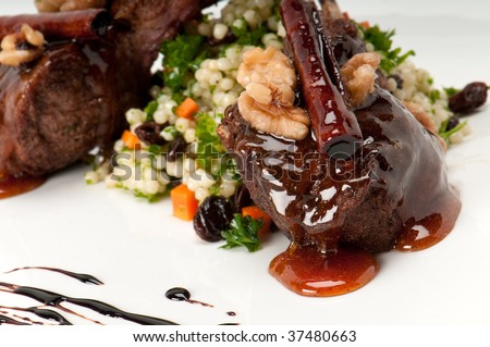 Close up of lamb chops with couscous and vegetables with a sauce of caramel, pepper and spices.