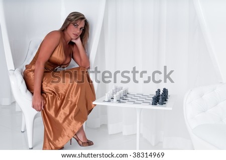 Young woman waiting for her partner to play a chess game in upscale location.