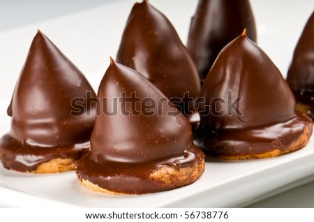 Close up of chocolate cones, over cookie filled with caramel.
