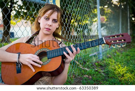 Young woman playing guitar outdoors. Space for copy.