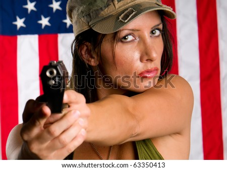 Young woman wearing military uniform pointing with gun. Use of selective focus. Focus in woman.