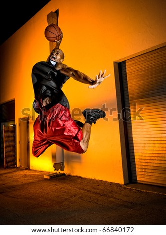 Basketball player jumping with ball in the street.