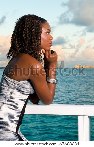 Young african american woman meditates in a terrace during sunset with the ocean in the background.