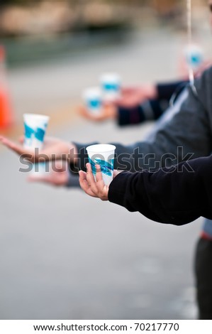 Close up of volunteers hands offering water during a Marathon. Use of selective focus. Lots of Copyspace.
