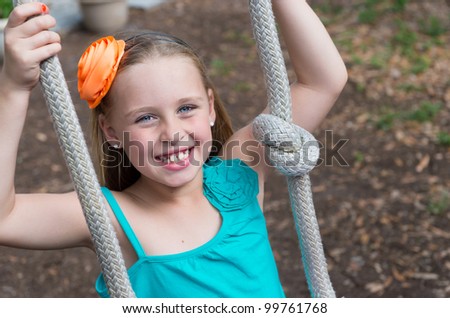 Happy girl swinging in a backyard very happy and smiling.