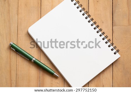 Pen and note book paper on wooden background