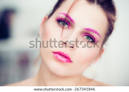 The woman with a bright pink make-up. Studio portrait.