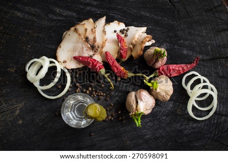 Bacon, garlic, onions, pepper and vodka on a dark wooden table