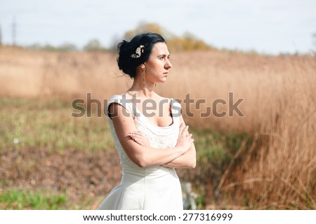 The lonely bride with flowers in a hairstyle in the middle of green fields