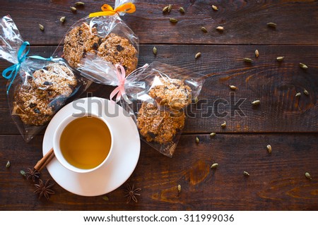 cup of herbal tea, the Indian spices and gift packing of homemade Christmas  cookies with dried fruits and nuts. Healthy food. Dark wooden background