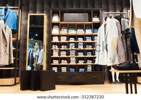 Shop with fashionable business and casual men's wear in city shopping center. Jackets, shirts and business suits. Packages with purchases.