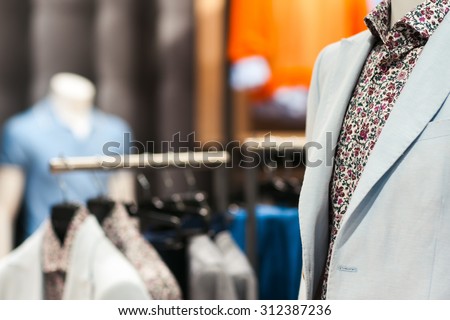 Interior of shop with fashionable business and casual  men\'s wear in city shopping center. A mannequin in an unusual shirt and a light jacket in the foreground