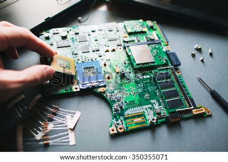 Technician analysis and plug in CPU microprocessor to motherboard socket. Workshop background