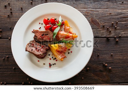 Medium rare pork steak with fresh vegetables. Food fotography of pork steak with potatoes and tomatoes cherry. Tasty cook meat with vegetables on dark wooden background.