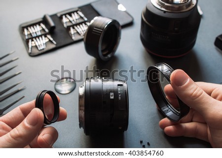 Photo camera lens repair set. Technician engineer disassembling, align and adjusts 50 mm 1.4 photo camera lens. Engineer\'s hands and maintenance support of broken photographic optic and optical part.