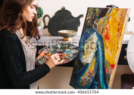 Creative contemporary painter paints a colorful abstract painting. Closeup of painting process in art workshop. Creative positive woman painter paints in her studio colorful abstract painting