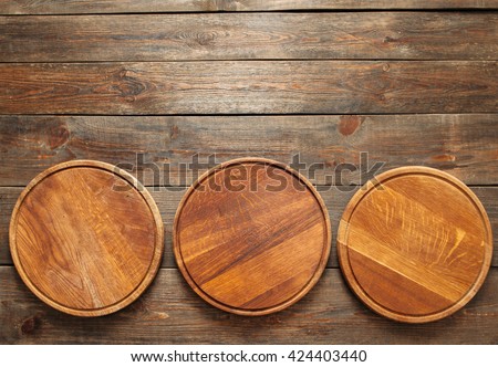 Three empty wooden pizza plates lie on the wooden table at the bottom of the picture. Copy space. Horizontal line. Flat lay of empty wooden pizza plates
