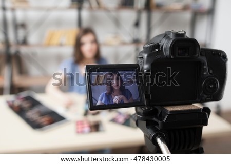 Young female beauty blogger on camera screen. Beautiful girl recording video at studio. Fashion, makeup, technology concept
