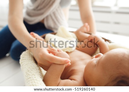 Mother massaging her newborn baby, close-up. Gymnastic, physical training, strengthening exercises for babies, early development, healthcare concept