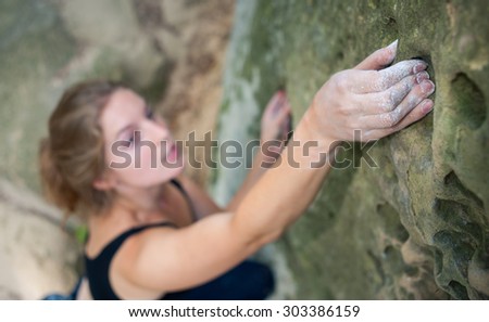Young woman climbing on large boulder outdoor summer day