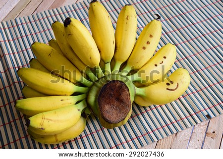 A Bunch of Bananas with three smile faces on table