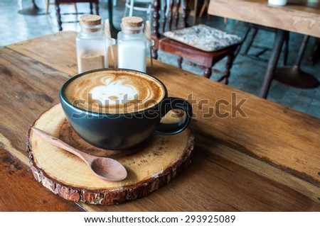Cute Hot Latte Coffee on wooden saucer in cafe