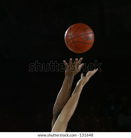 start of a basketball game with the jump ball as a white and black player go for the ball