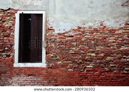 Old colorful brick wall with a door opened. Venice, Italy.