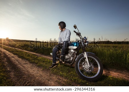 Man and his motorcycle in a cross country run on sunset