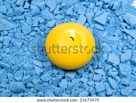 Yellow candle with fire on crushed chalk background
