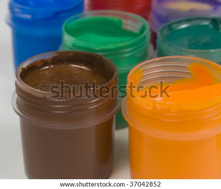 Collection of different color paints in individual open clear plastic containers, taken from overhead, isolated on a white background.