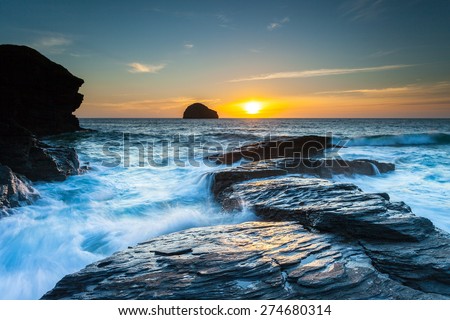 Gull Rock Sunset.  The sun sets beyond Gull Rock as the tide crashes in. At Trebarwith Strand, Cornwall, UK.