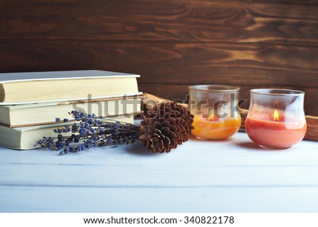 Still life of winter accessory. Pine cone, candles, books, bouquet lavender on a wooden background in vintage pink-violet colors