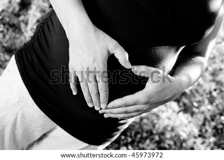 a pregnant woman making heart hands over her belly