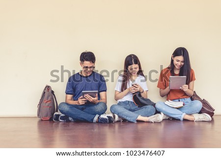 Group of Asian college student using tablet and mobile phone outside classroom. Happiness and Education learning concept. Back to school concept. Teen and people theme. Outdoors and Technology theme.