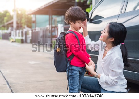 Mom preparing to send her children back to school at car in morning. Education and Back to school concept. Happy family and Loving of people theme.