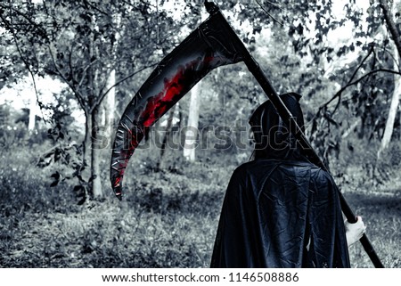Back view of demon witch with reaper and blood in the mystery forest. Horror and Ghost concept. Halloween day and Scary scene theme.